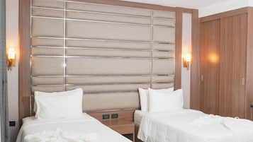 Ein Hotelzimmer mit zwei Betten, einem Holzkopfende, Nachttischlampen und einem Kleiderschrank.