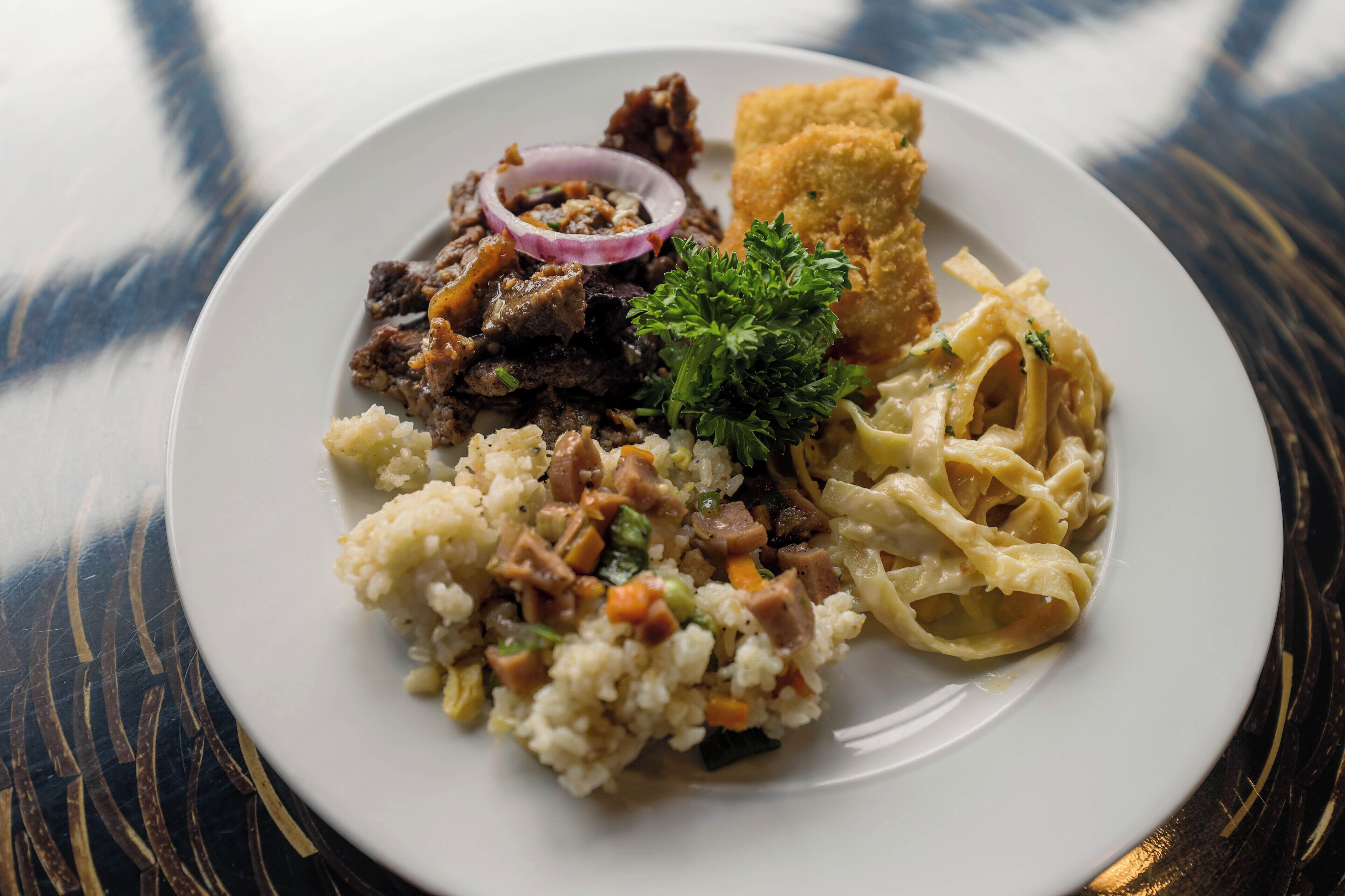 Une assiette de nourriture composée de riz, de viande et de légumes.