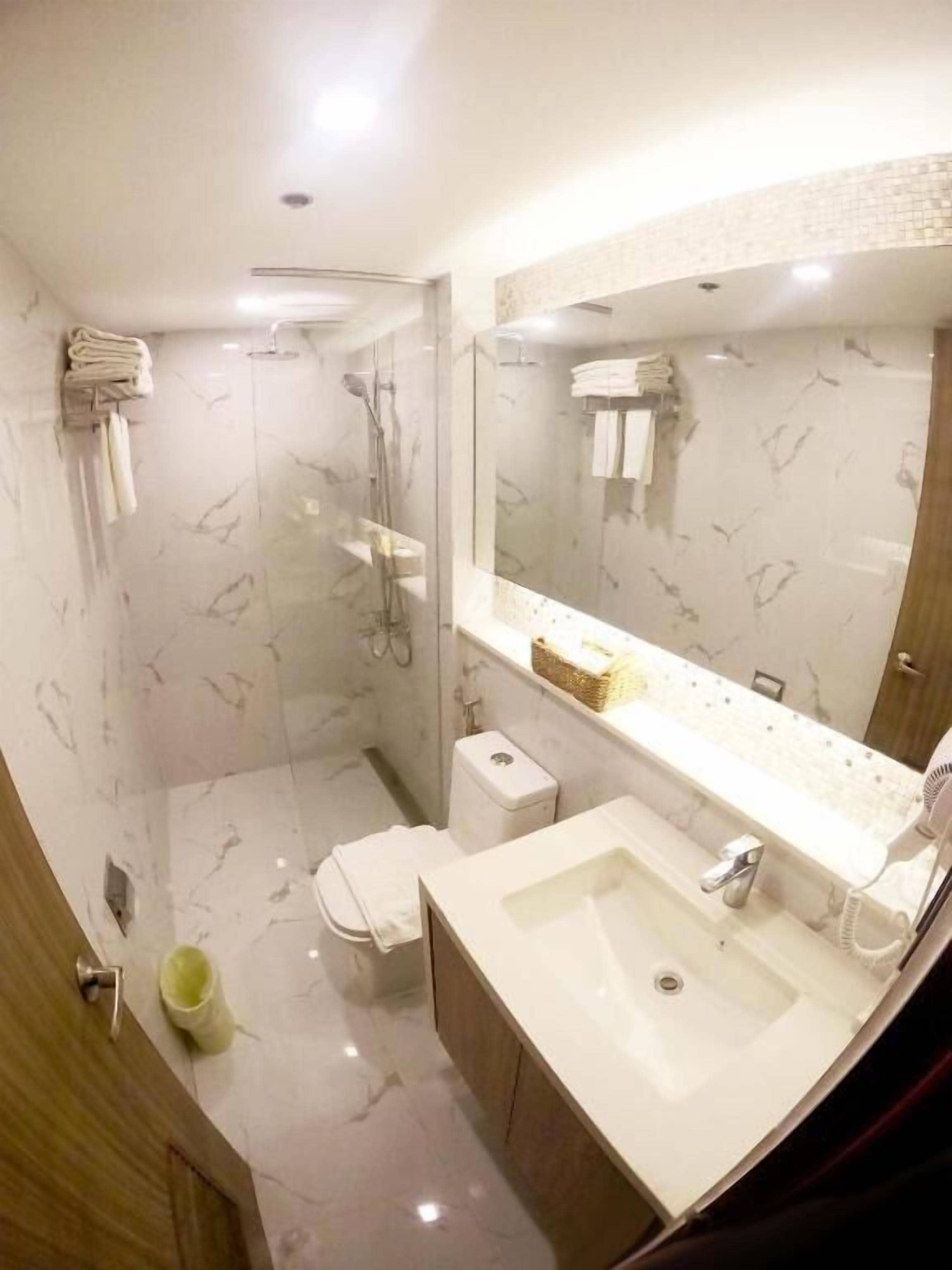 A modern bathroom with a shower, toilet, and sink.