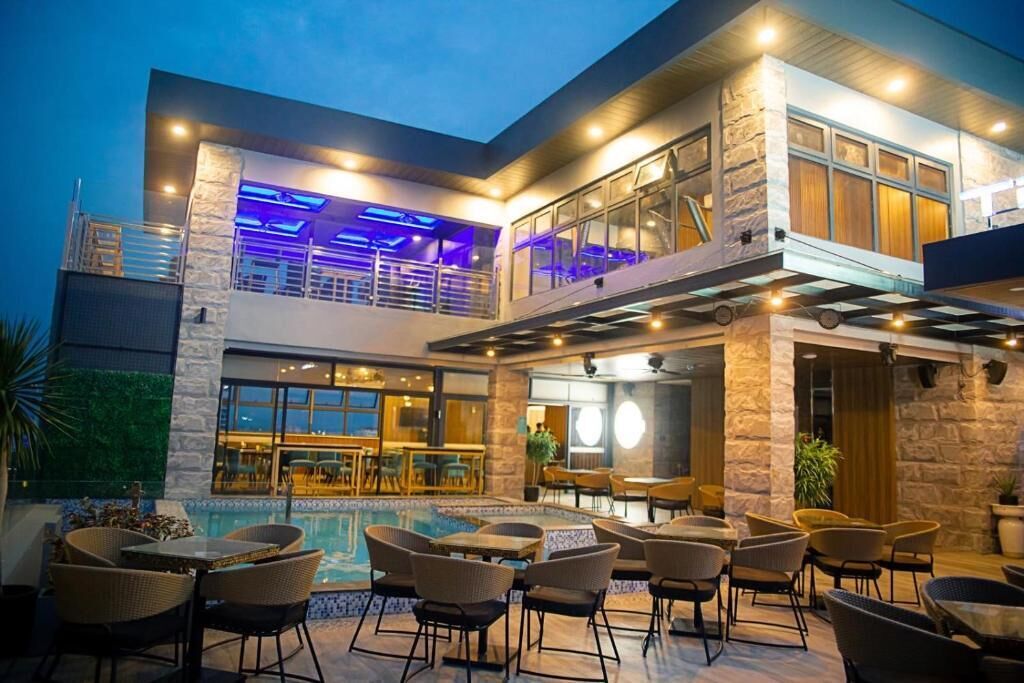 A two-story building with a pool, outdoor seating, and a bar area.