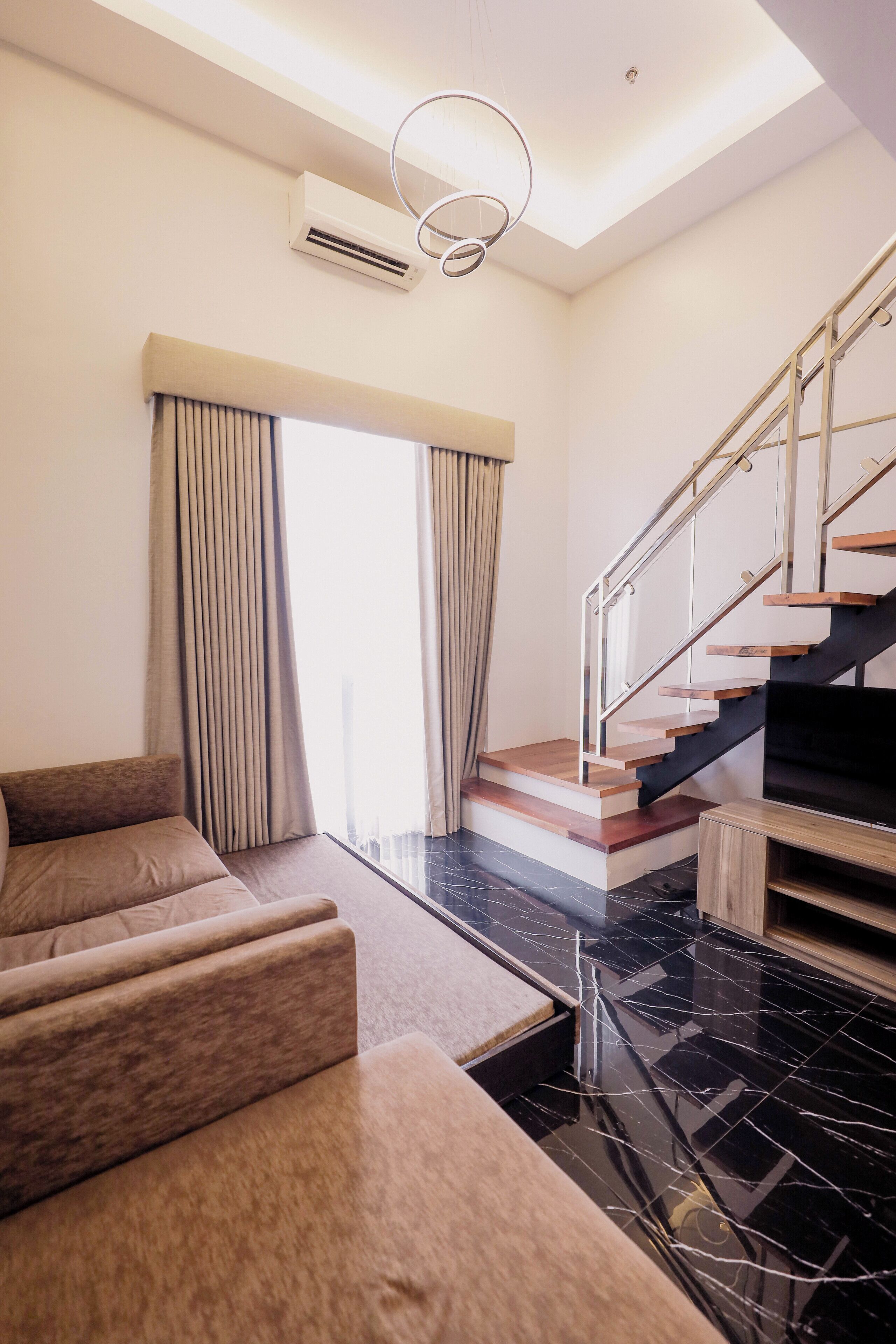 A modern living room with a sofa, a staircase, and a TV.