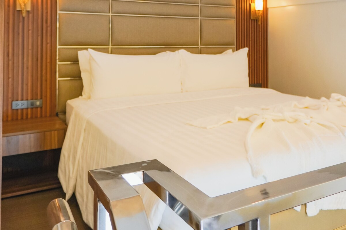 Ein Hotelzimmer mit einem großen Bett, einem Kopfteil mit vertikalen Paneelen, zwei Wandleuchten und einer Deckenleuchte.
