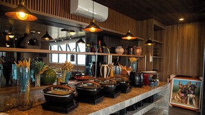 A kitchen counter with various appliances and utensils, a framed picture of dogs, and hanging pendant lights. - El Vistra Hotel (Angeles City)