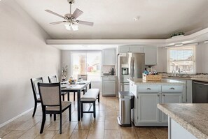 Eine moderne Küche mit weißen Schränken, einem integrierten Kühlschrank und einem Essbereich mit Tisch und Stühlen.