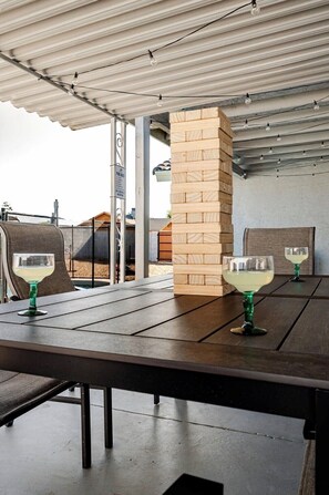 Ein Sitzbereich im Freien mit Tisch, Stühlen und zwei Gläsern Weißwein.
