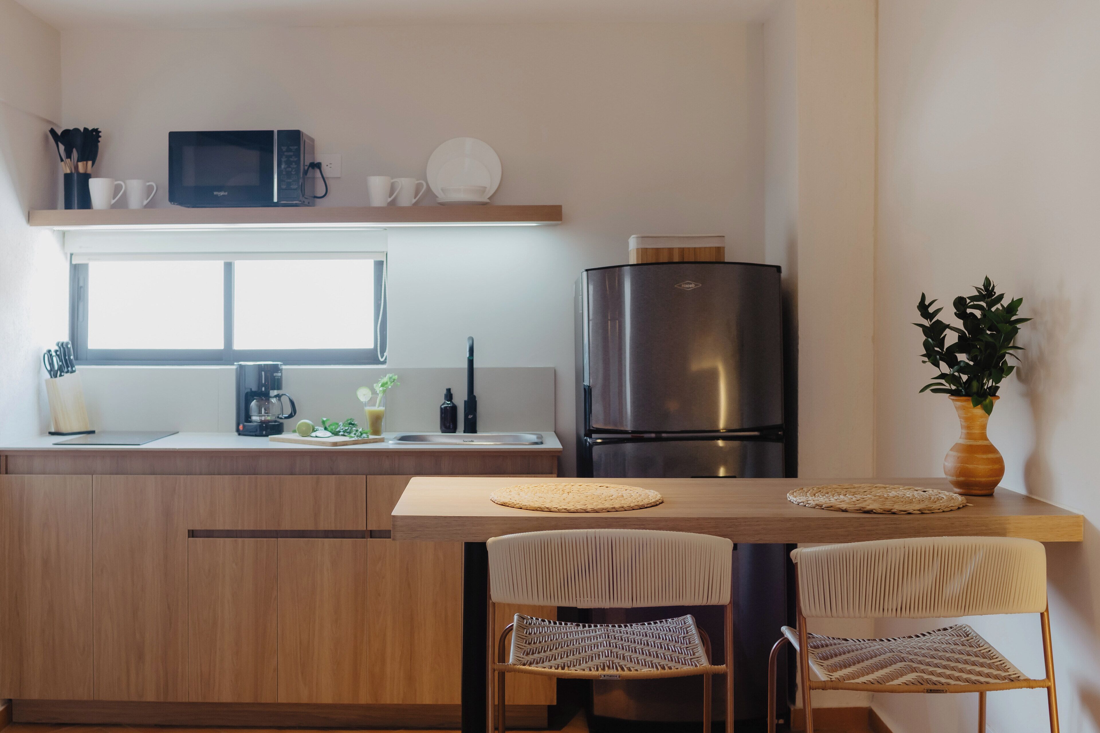 A modern kitchen with a microwave, coffee maker, and stainless steel refrigerator.