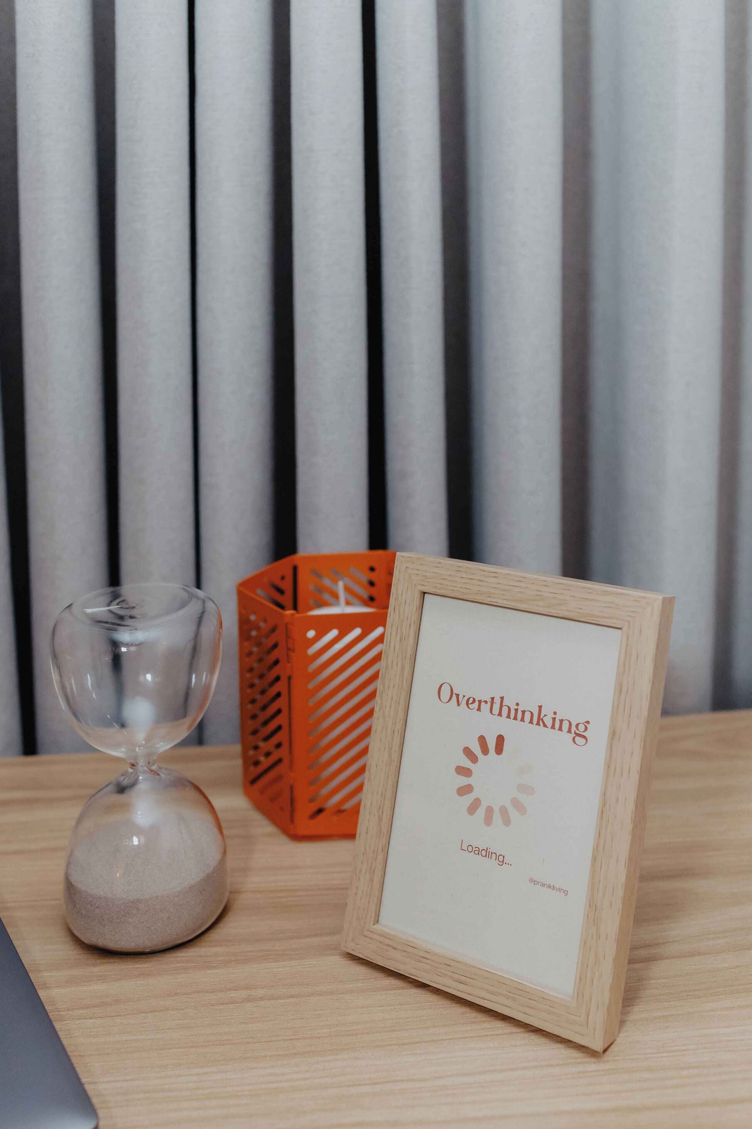Une pancarte encadrée avec les mots « Trop réfléchir » et « Chargement en cours… » posée sur une table en bois.