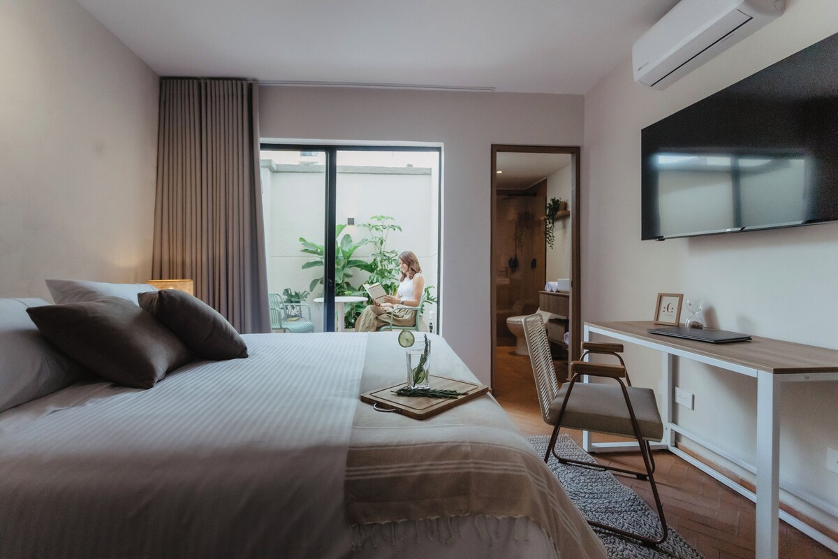A modern hotel room with a bed, desk, and TV.