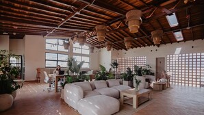 A spacious living area with a large sectional sofa, wooden flooring, and a high ceiling with exposed beams. - Pranik Living Co-mmunity (Medellín)