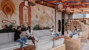 Un espacio al aire libre moderno con un sofá, sillas de mimbre y una mesa de centro de madera.