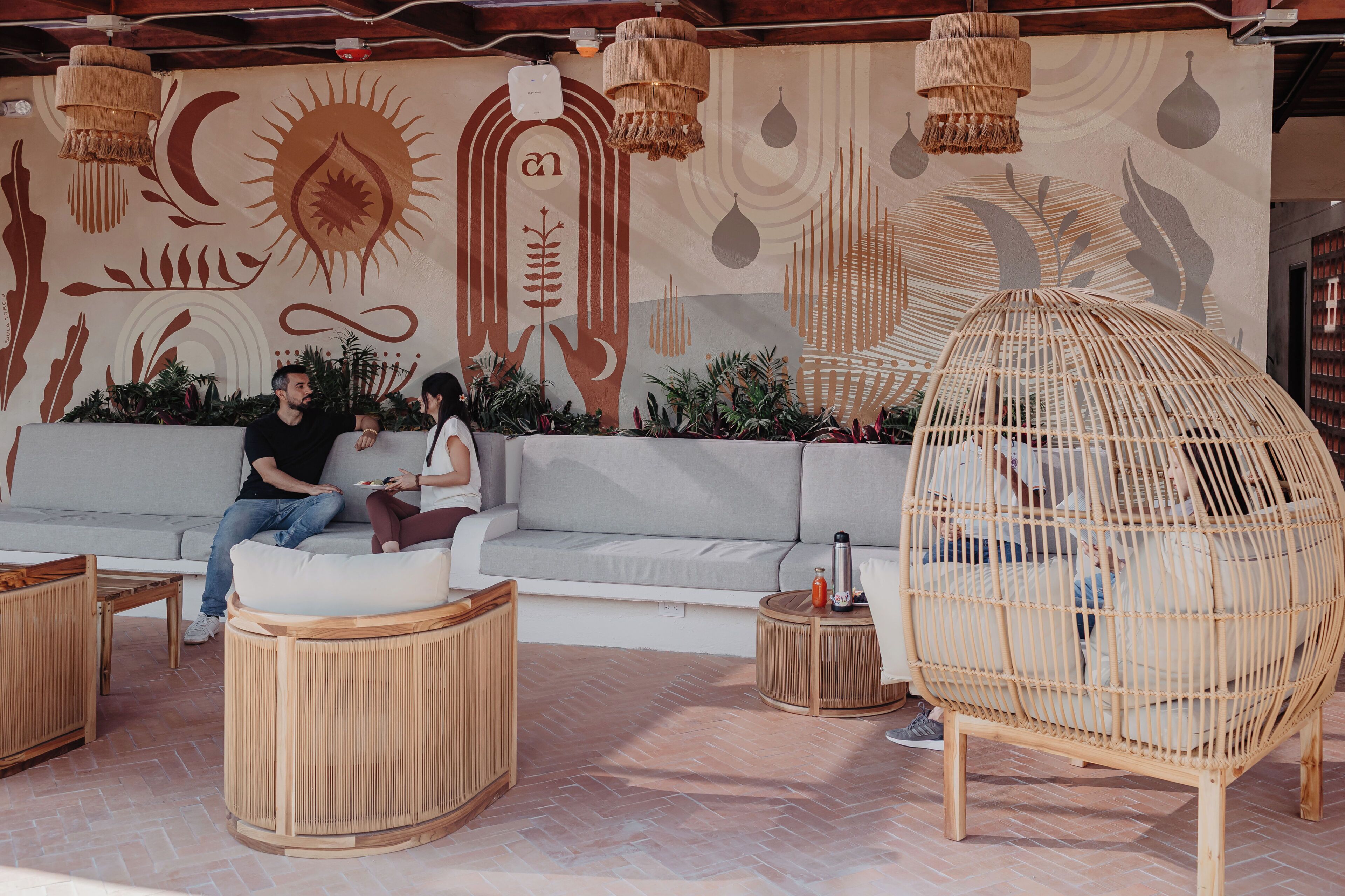 A modern outdoor seating area with a sofa, round wooden tables, and a woven chair.