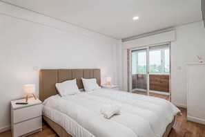 Ein Schlafzimmer mit einem Bett, Nachttischen, einer Lampe, einem Handtuch und Blick ins Freie.