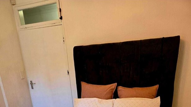 A bed with a headboard, two pillows, and a brown blanket. - Room-aquasaints Guest Lodge 2 (Johannesburg)