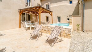 Ein Poolbereich mit Liegestühlen, einer Pergola und einer Steinmauer.