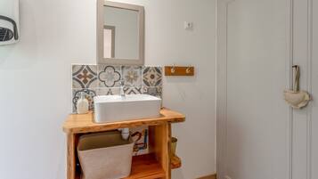 Un bagno con un mobile lavabo in legno, un lavandino bianco, uno specchio e piastrelle decorate.