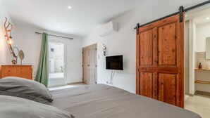 Ein Schlafzimmer mit einem Bett, einem Fernseher, einem Holzschrank und einer Schiebetür.