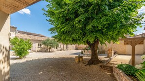 Ein Innenhof mit Baum, Kiesgrund und Gebäuden im Hintergrund.