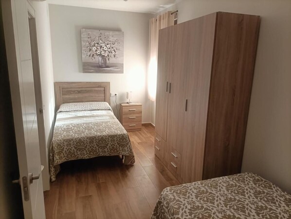 Un dormitorio con cama, mesita de noche, armario y un cuadro en la pared.