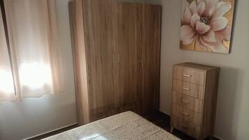 Un dormitorio con cama, armario, aparador y un cuadro en la pared.