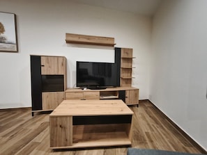 Un salon moderne avec un téléviseur à écran plat, des meubles en bois et un tableau encadré au mur.