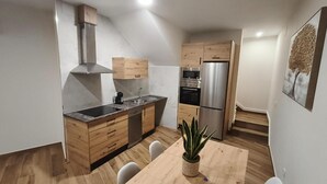 A modern kitchen with wooden cabinets, a stainless steel refrigerator, and a dining table with chairs. - El Huertecillo 1 Apartment, Renaissance Village in La Mancha (Villanueva de los Infantes)