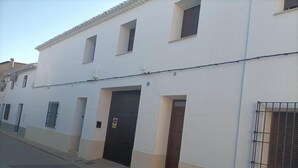 A white building with multiple windows, a gated entrance, and a visible door. - El Huertecillo 1 Apartment, Renaissance Village in La Mancha (Villanueva de los Infantes)