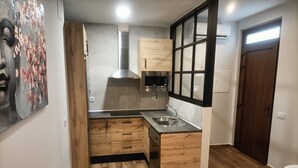 A compact kitchen with wooden cabinets, a stainless steel sink, and a microwave.
