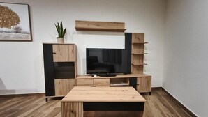 A modern living room with a wooden entertainment center, a flat-screen TV, and a potted plant.