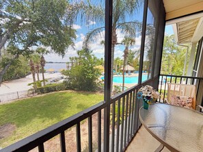 Ein Balkon mit Blick auf einen Swimmingpool, Palmen und eine Rasenfläche.