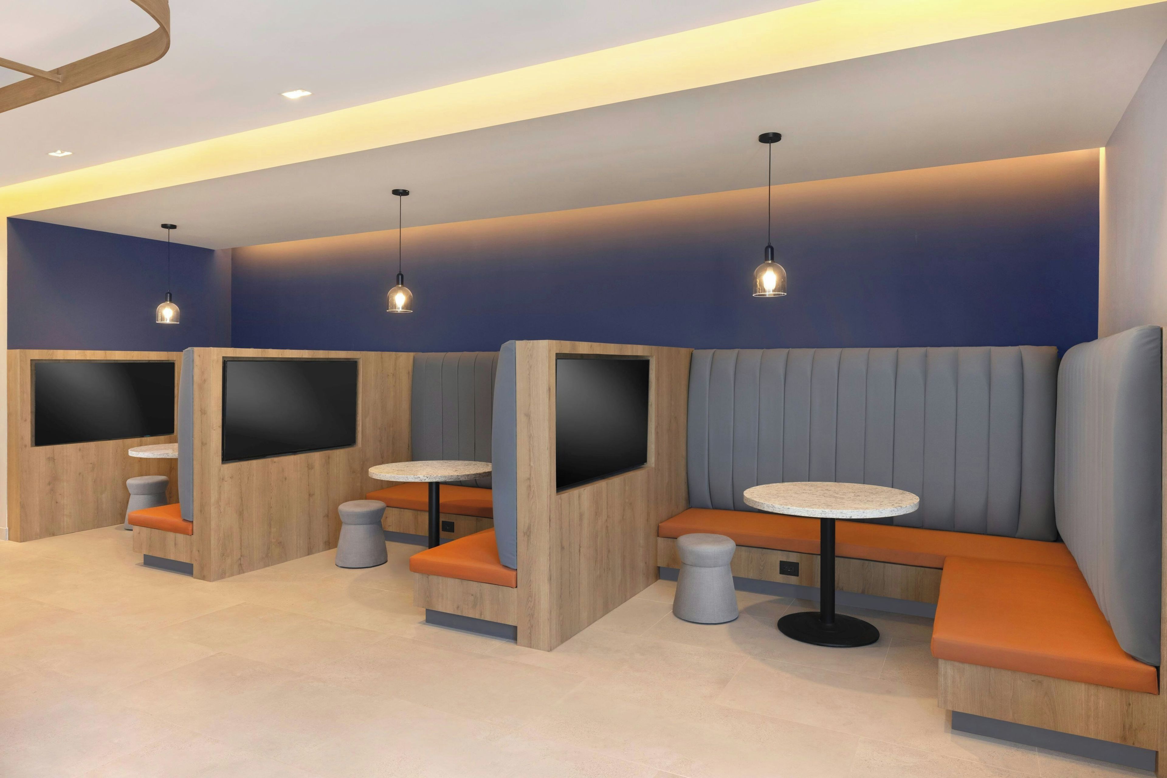 A modern seating area with built-in booths, round tables, and pendant lighting.