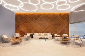 Un espace de détente moderne avec un mur orné d’un motif géométrique, un ensemble de canapés et une table basse.