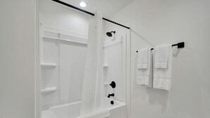 A bathroom with a shower, a toilet, and a towel rack.