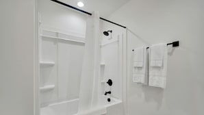 A bathroom with a shower, a toilet, and a towel rack.
