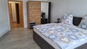 A bedroom with a bed, a wardrobe, a nightstand, and a door leading to another room. - NEW! Apartment Calbe an der Saale (Calbe)