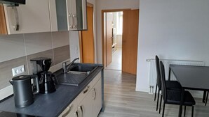 A modern kitchen with a coffee maker, a kettle, and a toaster. There is a dining table with chairs and a radiator. - NEW! Apartment Calbe an der Saale (Calbe)