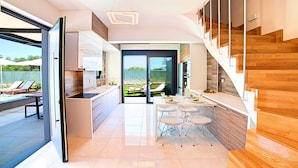 Eine moderne Küche mit Essbereich, einer Treppe und Blick auf die Terrasse.