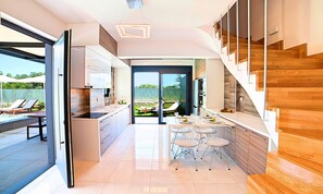 Eine moderne Küche mit Essbereich, einer Treppe und Blick auf die Terrasse.