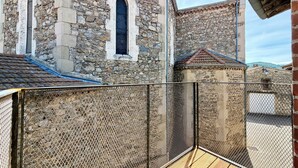 A stone building with arched windows and a metal fence. - Le Chai - Gervans (Gervans)