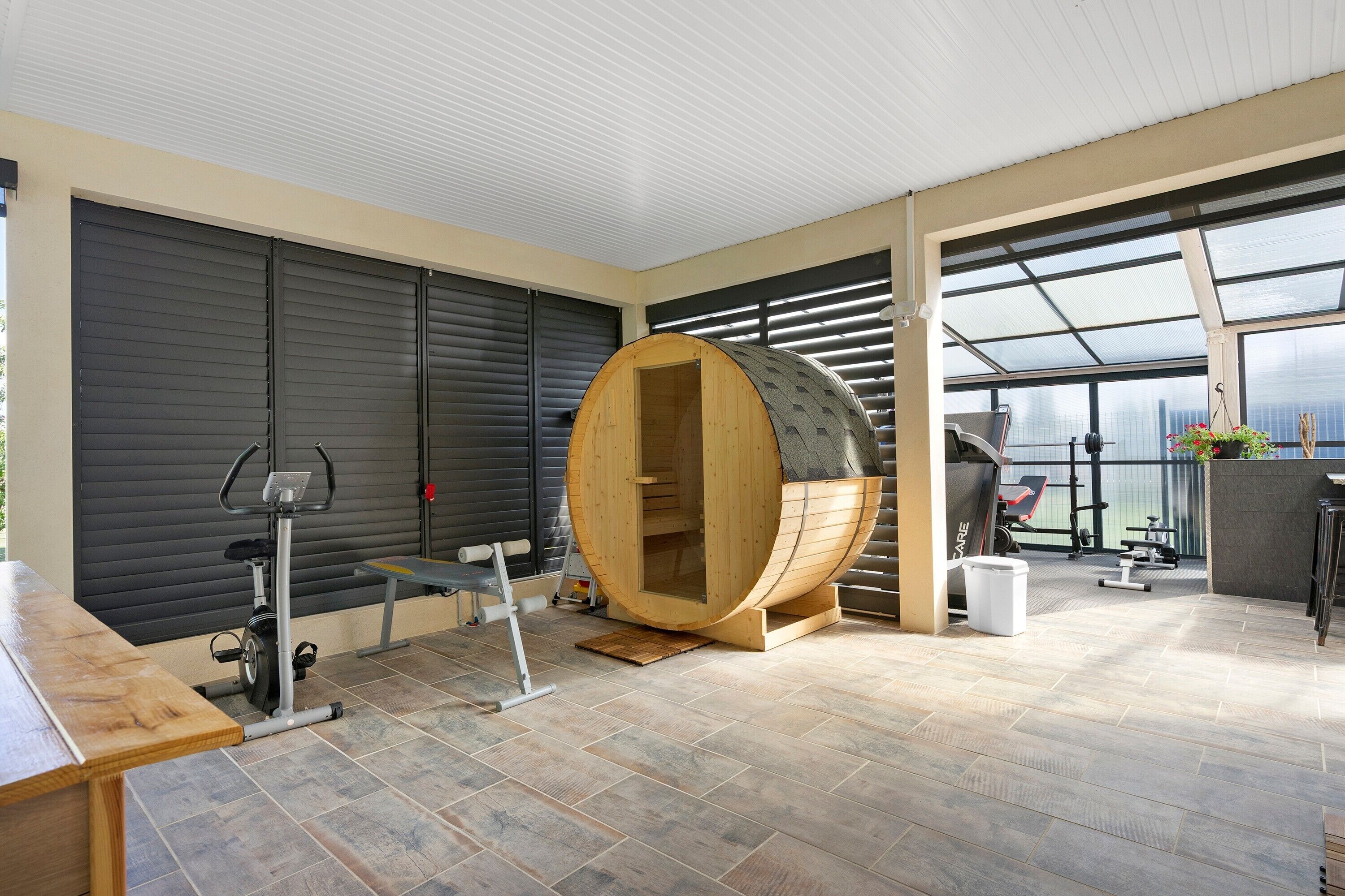 A gym with exercise equipment, a sauna, and large windows.