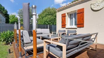 Eine Terrasss mit einer Couch, Sesseln und einem Tisch.