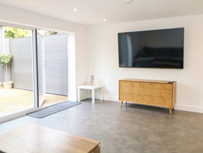 Ein modernes Interieur mit einer Schiebetür aus Glas, einem wandmontierten Flachbildfernseher, einem kleinen weißen Beistelltisch und einem Holzschrank.