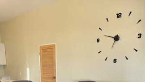 Een woonkamer met twee grijze banken, een kamerkleed met patroon en een wandklok.
