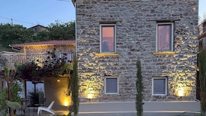 Une maison en pierre avec un jardin, un espace extérieur aménagé et une vue sur la mer.