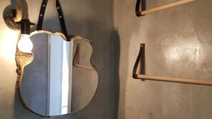 Une salle de bain avec un miroir rond, un lavabo blanc et deux porte-serviettes.