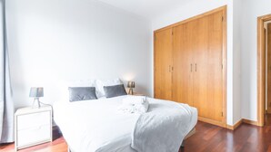 Ein Schlafzimmer mit Bett, Nachttische, einem Kleiderschrank und einem Beistelltisch.