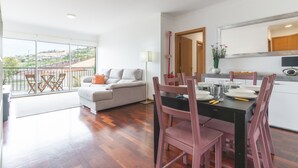 Ein modernes Wohnzimmer mit Sofa, Esstisch, Stühlen und einem Balkon mit Blick.