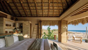 Un dormitorio con una cama grande, una escalera de madera y vistas a la playa.