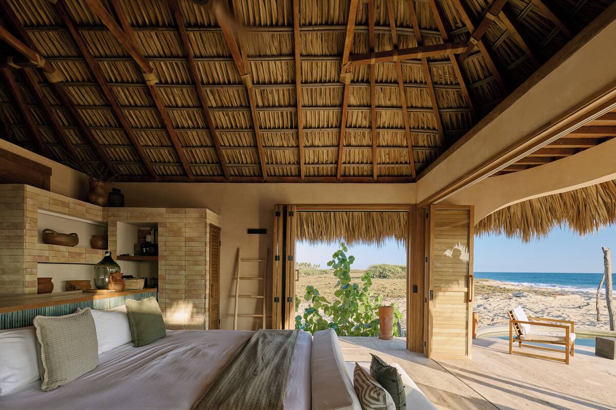 Un dormitorio con una cama grande, una escalera de madera y vistas a la playa.