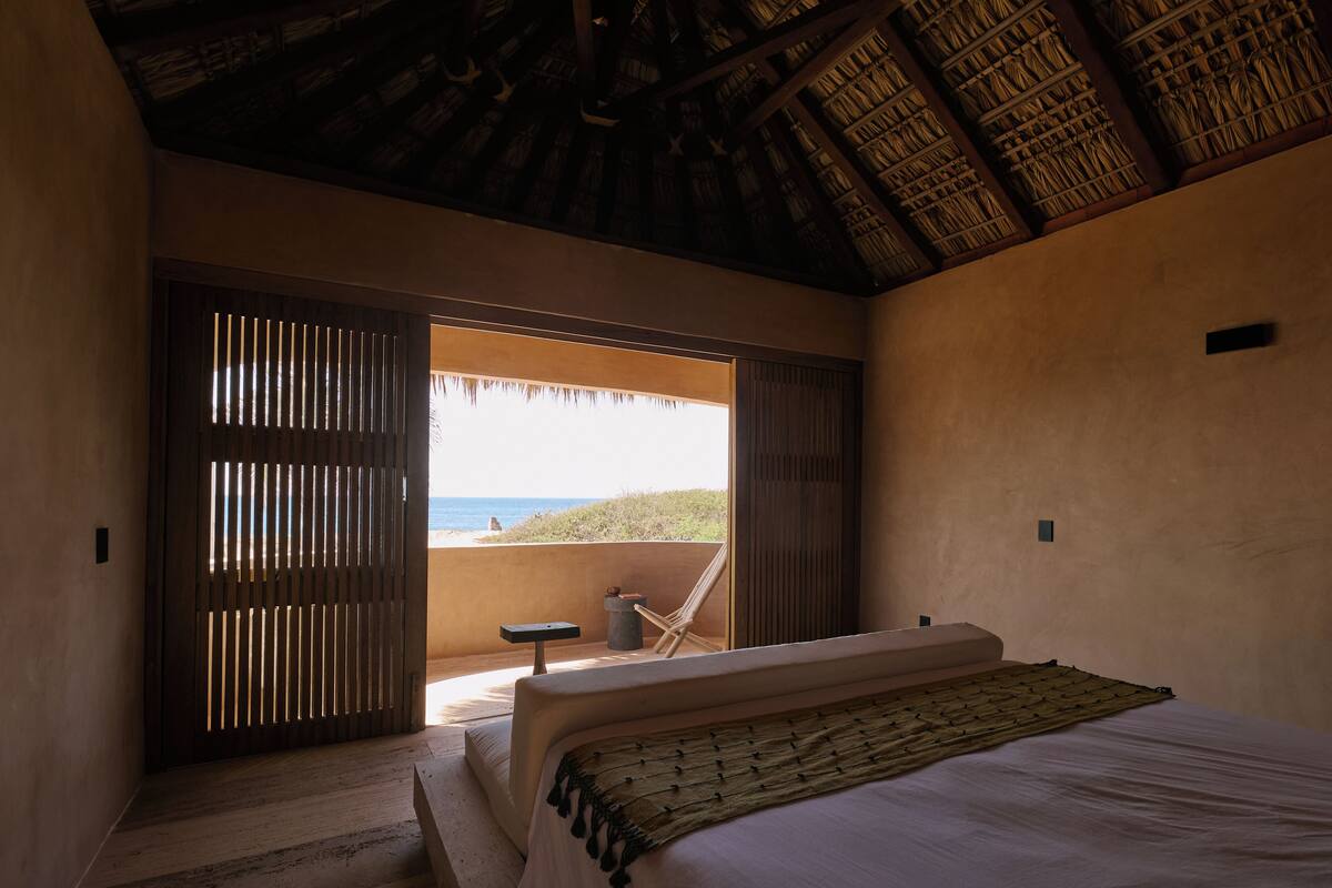 Un dormitorio con cama, una silla y vistas a la playa.