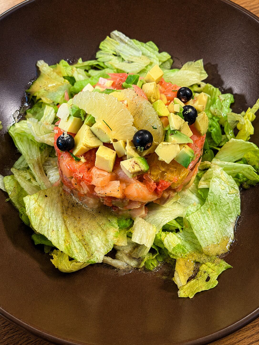 Une salade composée d’avocat, de tomates et d’olives noires, servie sur un lit de laitue.